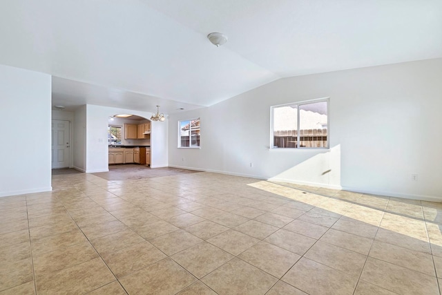 unfurnished living room with lofted ceiling, light tile patterned floors, a wealth of natural light, and an inviting chandelier