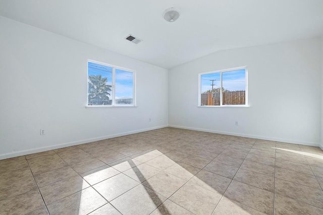 tiled spare room with vaulted ceiling