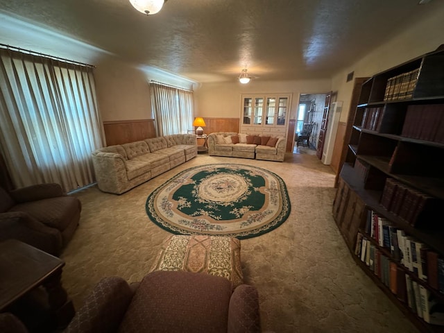 carpeted living area with wooden walls and a wainscoted wall