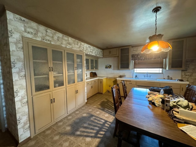 kitchen featuring tile patterned floors, pendant lighting, a sink, light countertops, and glass insert cabinets