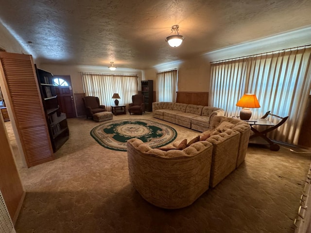 living area with carpet flooring, wainscoting, and a textured ceiling