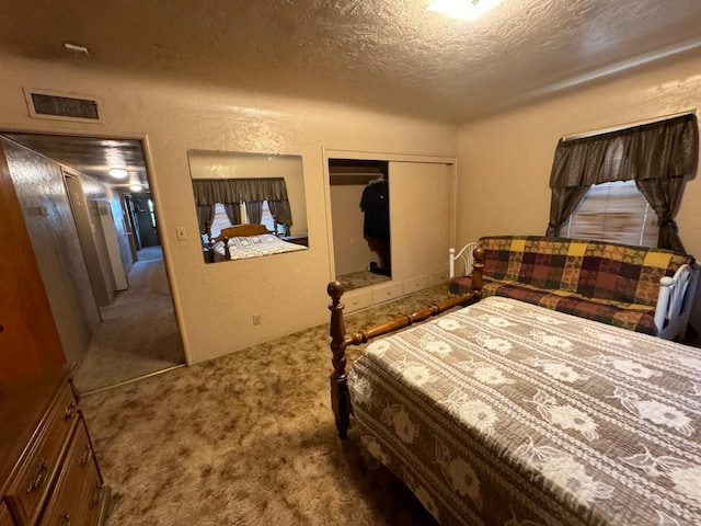 bedroom featuring visible vents, a textured ceiling, carpet floors, and a textured wall