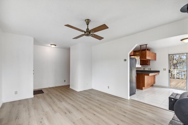 unfurnished living room featuring ceiling fan and light wood-type flooring