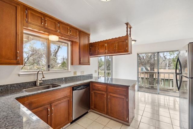 kitchen with stainless steel appliances, sink, light tile patterned floors, kitchen peninsula, and a healthy amount of sunlight