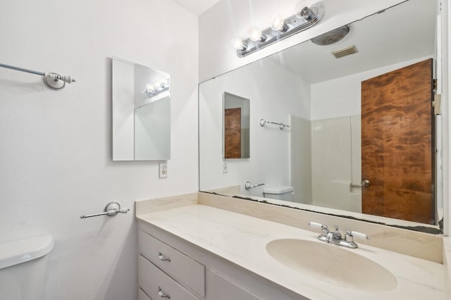 bathroom featuring toilet, a shower, and vanity