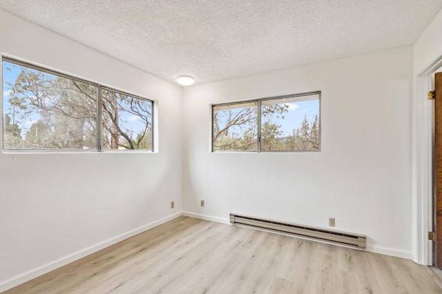 empty room featuring a textured ceiling, light hardwood / wood-style flooring, and a baseboard heating unit