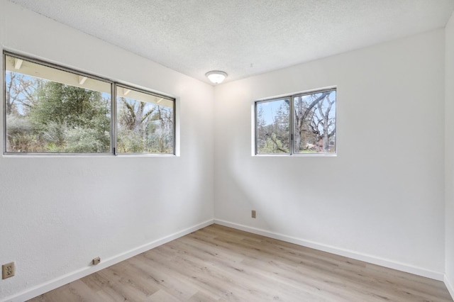 spare room featuring a textured ceiling and light hardwood / wood-style floors