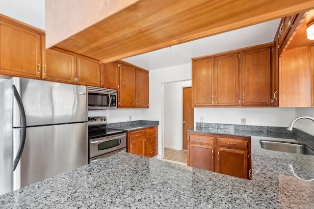 kitchen featuring sink, dark stone countertops, and appliances with stainless steel finishes