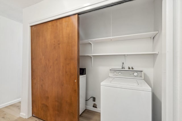 laundry room with washing machine and dryer and light hardwood / wood-style floors