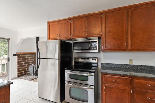 kitchen featuring stainless steel appliances, light tile patterned flooring, and dark stone counters