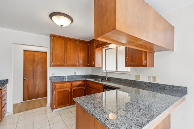 kitchen with sink, dark stone countertops, kitchen peninsula, and light tile patterned floors