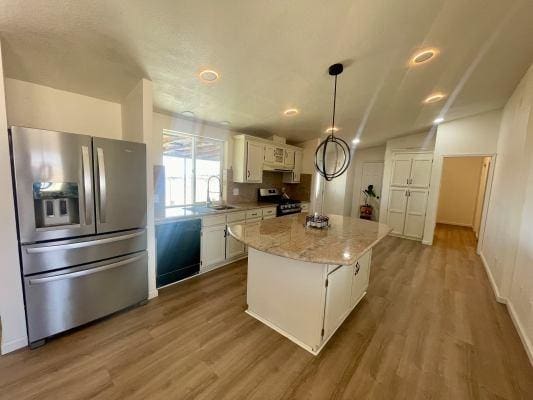 kitchen featuring decorative light fixtures, white cabinetry, sink, a center island, and stainless steel appliances