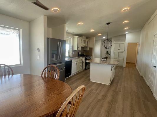 kitchen with dark wood-type flooring, white cabinetry, a center island, appliances with stainless steel finishes, and pendant lighting