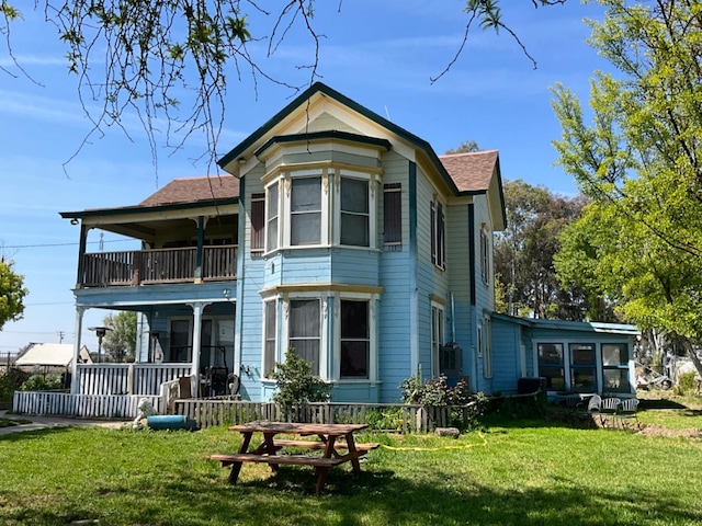 rear view of house featuring a balcony and a yard