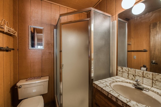 bathroom with vanity, toilet, an enclosed shower, and wood walls