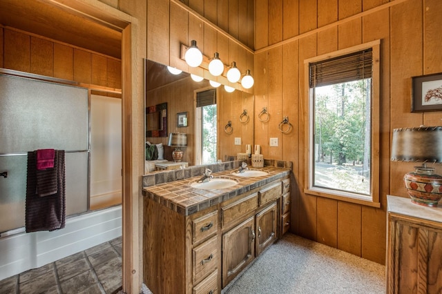 bathroom with vanity, a wealth of natural light, shower / bath combination with glass door, and wood walls