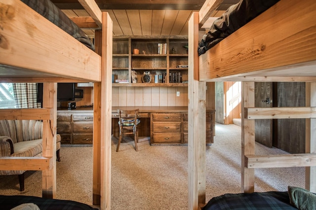 interior space with built in desk, light carpet, and wood walls