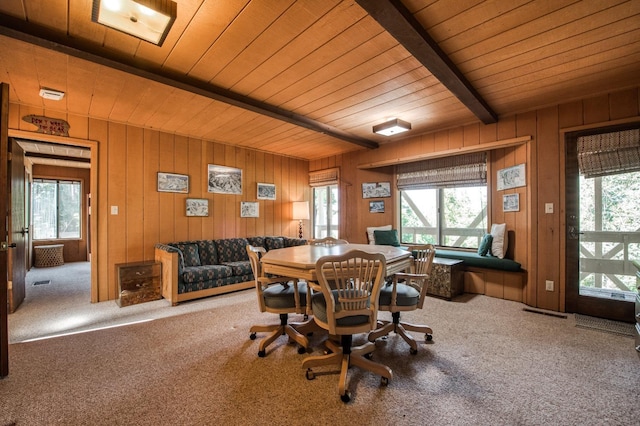 carpeted dining area with plenty of natural light, wooden ceiling, beam ceiling, and wood walls