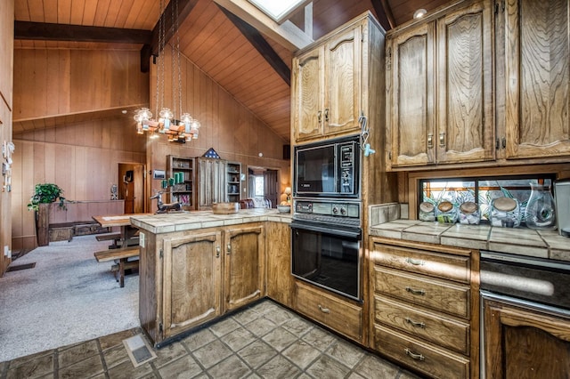 kitchen featuring tile countertops, pendant lighting, vaulted ceiling with beams, black appliances, and light carpet