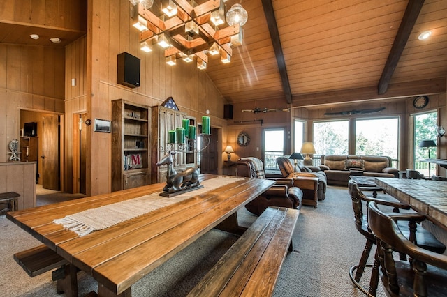 dining room featuring carpet, beamed ceiling, and wood walls