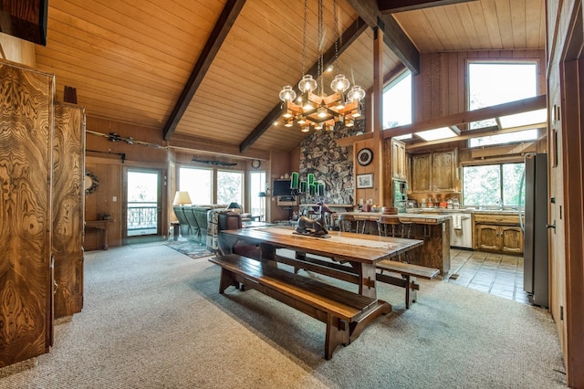 carpeted dining room with beam ceiling, high vaulted ceiling, and a healthy amount of sunlight