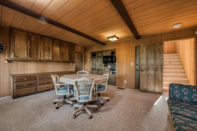 dining space featuring beamed ceiling, wood ceiling, wooden walls, and carpet floors