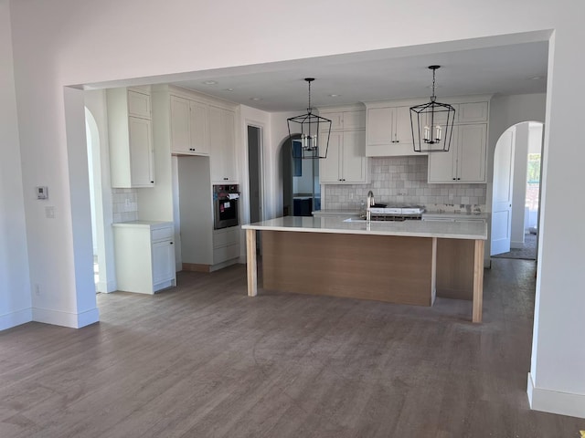 kitchen featuring white cabinetry, oven, light hardwood / wood-style flooring, and a center island with sink