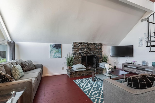 living area featuring baseboards, vaulted ceiling, dark wood finished floors, and a stone fireplace