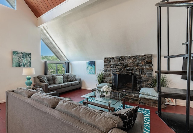 living room featuring lofted ceiling, baseboards, wood finished floors, and a stone fireplace