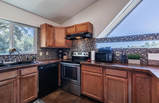 kitchen featuring lofted ceiling, dark countertops, a sink, under cabinet range hood, and black appliances