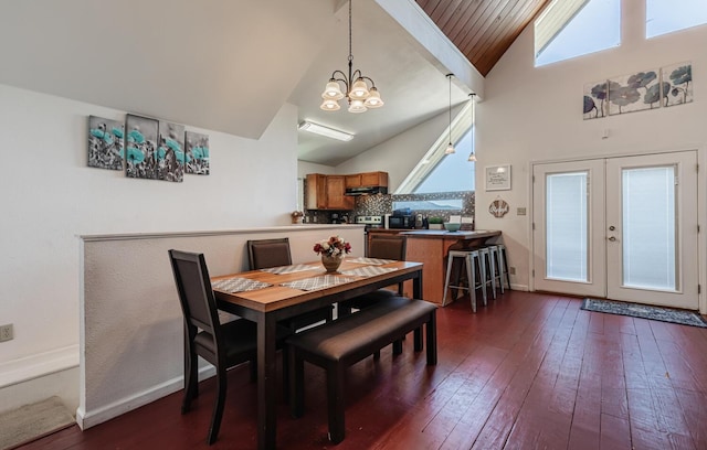 dining area featuring french doors, a notable chandelier, dark wood finished floors, high vaulted ceiling, and baseboards