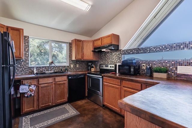 kitchen featuring lofted ceiling, dark countertops, a sink, under cabinet range hood, and black appliances