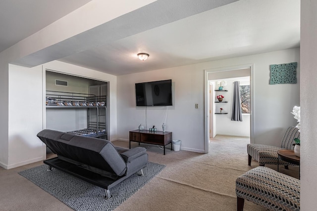 living area with baseboards, visible vents, and light colored carpet