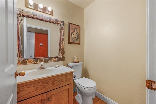 bathroom with toilet, hardwood / wood-style flooring, and vanity