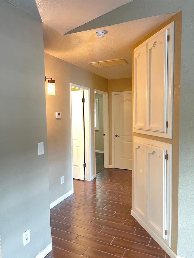 corridor featuring a textured ceiling and dark wood-type flooring