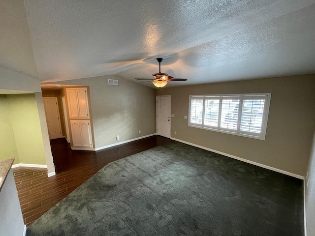 empty room featuring ceiling fan, a textured ceiling, lofted ceiling, and dark hardwood / wood-style flooring