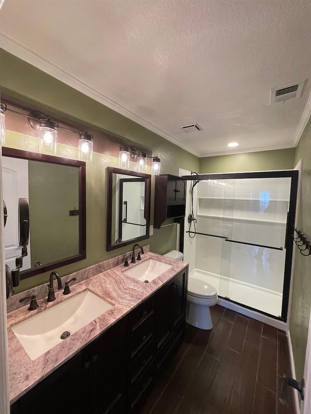 bathroom with hardwood / wood-style floors, a textured ceiling, walk in shower, toilet, and vanity