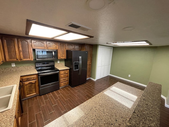 kitchen with dark wood-type flooring, stainless steel appliances, and a textured ceiling