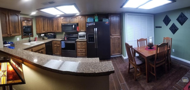 kitchen featuring kitchen peninsula, dark hardwood / wood-style flooring, light stone countertops, black appliances, and sink