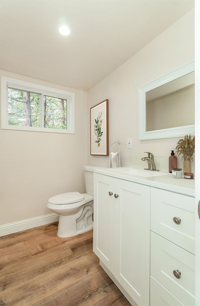 bathroom with hardwood / wood-style flooring, toilet, and vanity