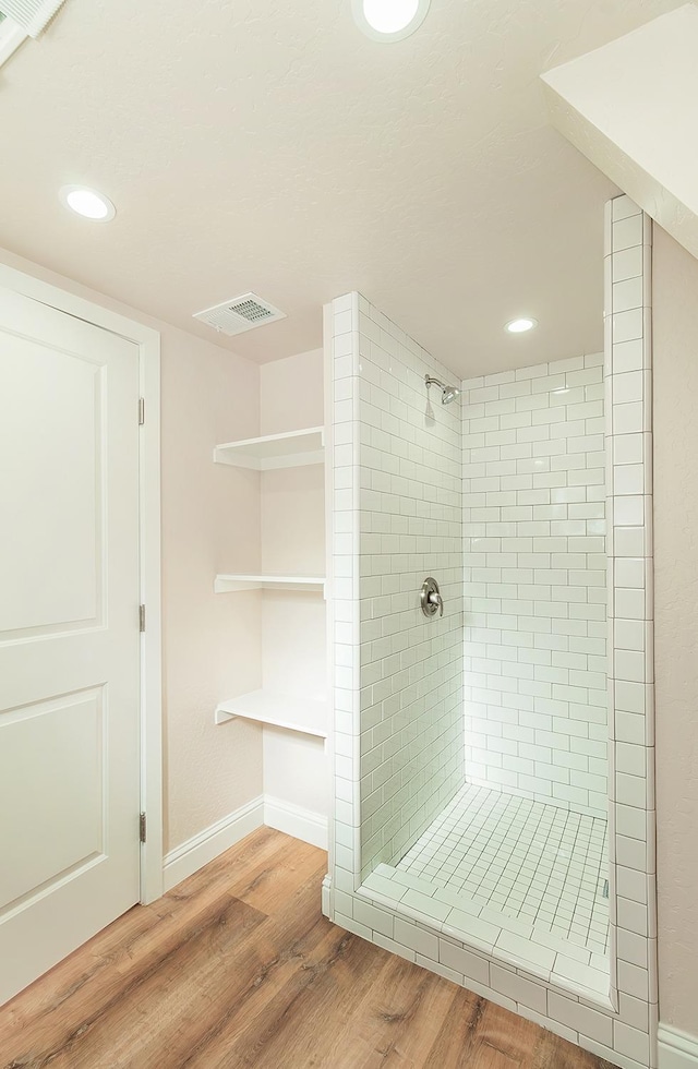 bathroom with tiled shower and hardwood / wood-style floors