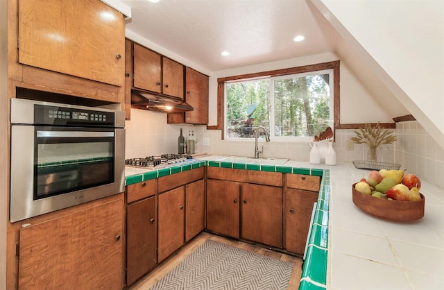 kitchen with sink, tile counters, backsplash, and stainless steel appliances