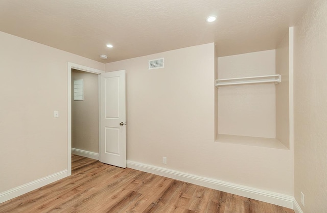 unfurnished room featuring light hardwood / wood-style flooring and a textured ceiling