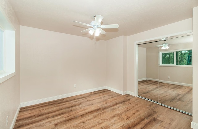 unfurnished bedroom with ceiling fan, a closet, and light hardwood / wood-style floors