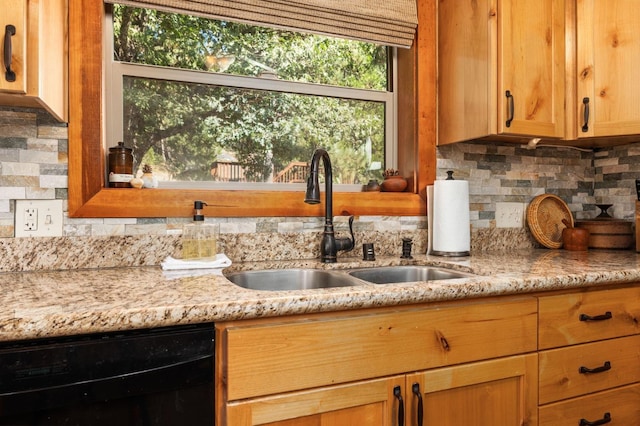 kitchen featuring tasteful backsplash, black dishwasher, sink, and light stone counters