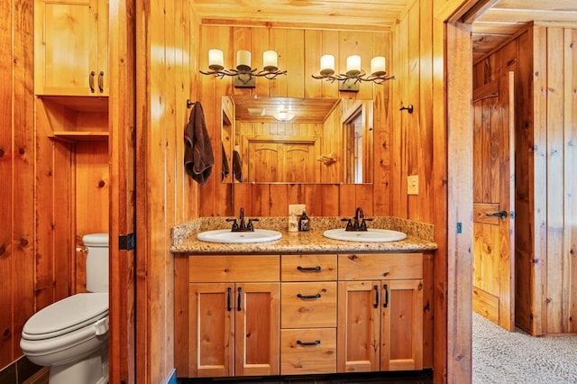 bathroom with vanity, toilet, and wood walls