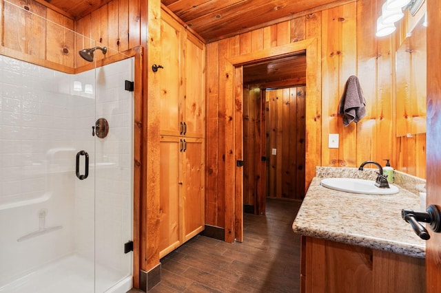 bathroom with walk in shower, wood ceiling, wood-type flooring, vanity, and wooden walls