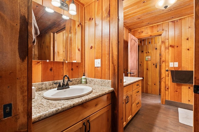 bathroom featuring vanity, hardwood / wood-style floors, wooden ceiling, and wood walls