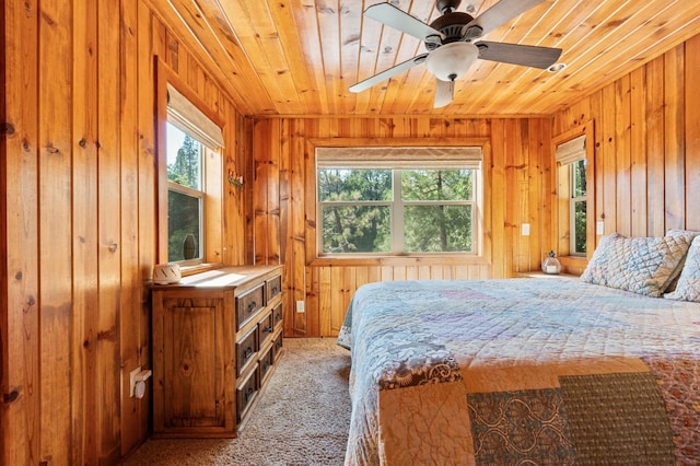 carpeted bedroom with multiple windows, wood ceiling, ceiling fan, and wood walls