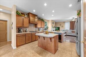 kitchen with a kitchen bar, stainless steel fridge, backsplash, light tile patterned floors, and a kitchen island